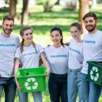 young-volunteers-with-green-recycling-boxes-for-trash-standing-in-park.jpg